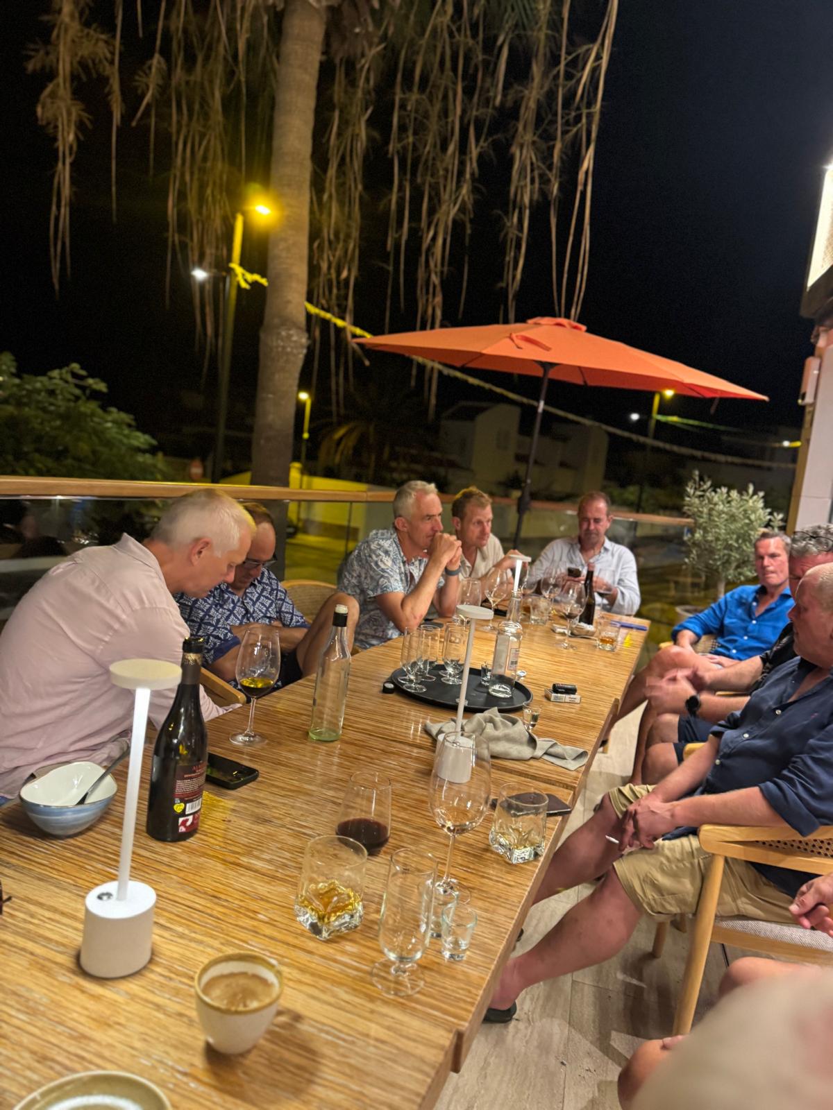 The group around an outdoor dinner table at night