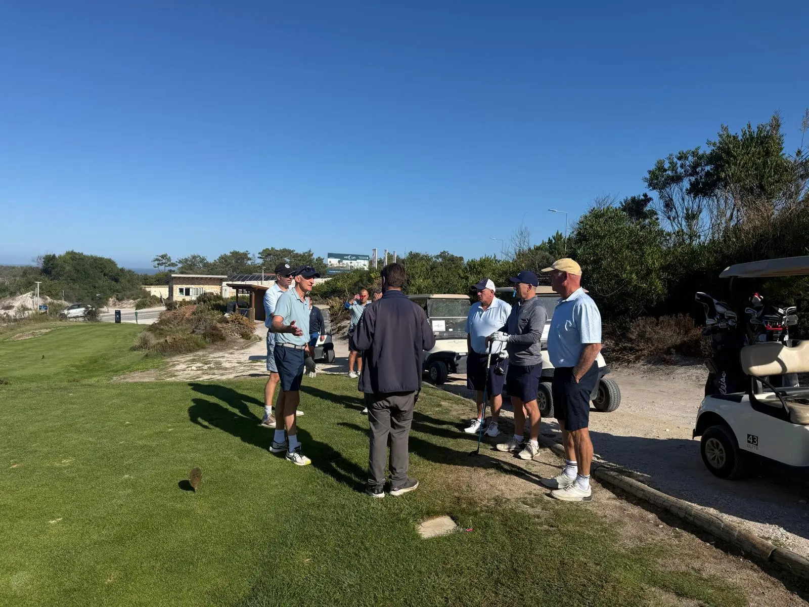 Golfers gathered beside buggies on a tee